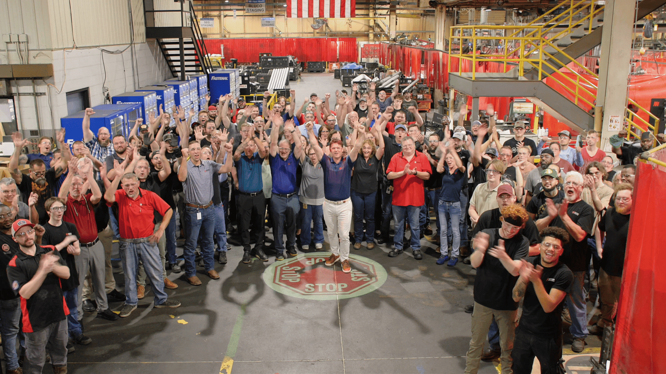 Group of Morton Industries team members on the manufacturing floor, smiling and raising their hands in celebration.